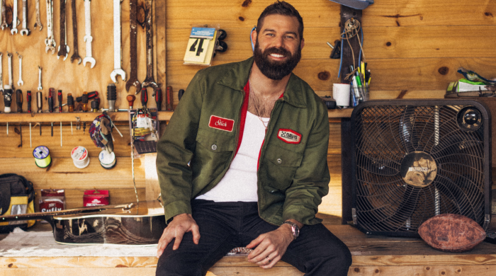 Man sitting on a workbench with tools behind him